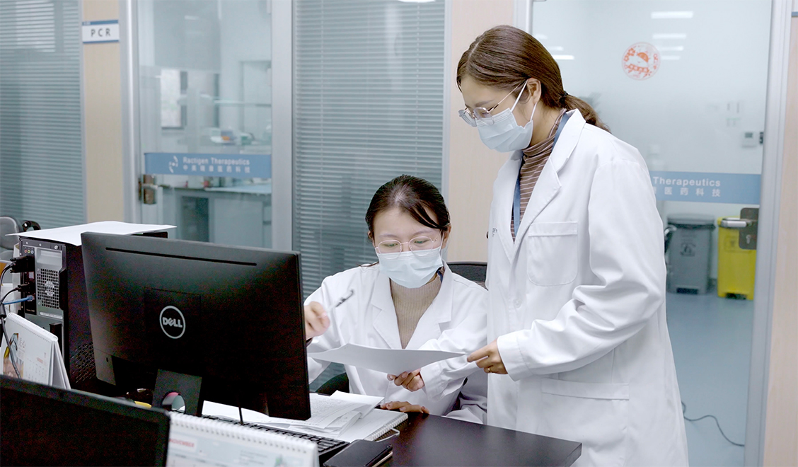 Two women in lab coats working at a computer